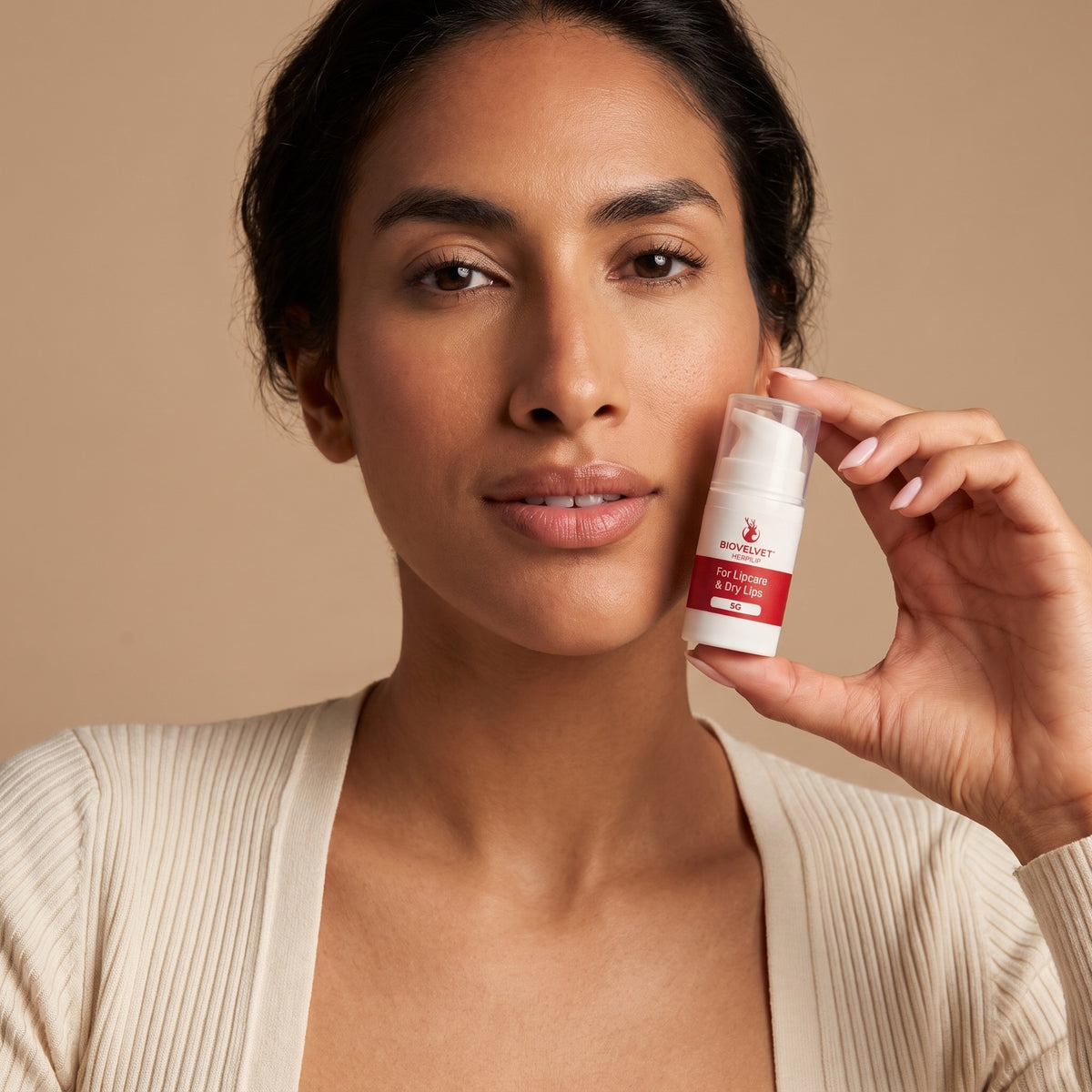 Woman holding the BIOVELVET Herpilip lip balm pump near her cheek